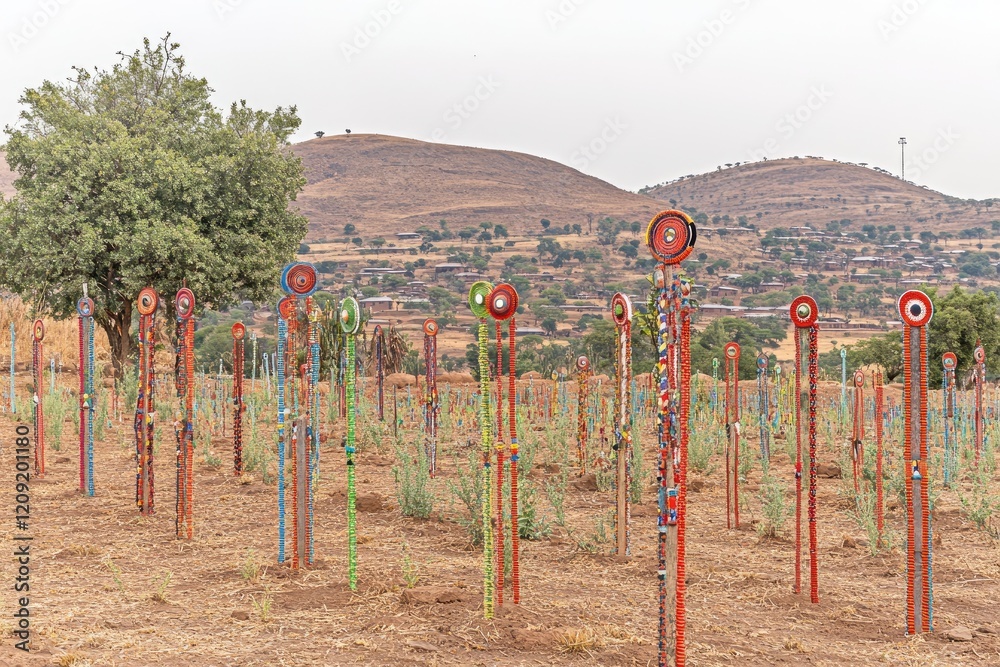 Fototapeta premium Colorful beaded poles in rural African landscape; community art installation