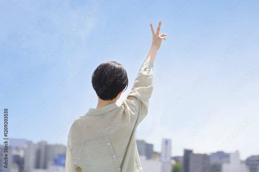 屋上でピースサインをする若い女性