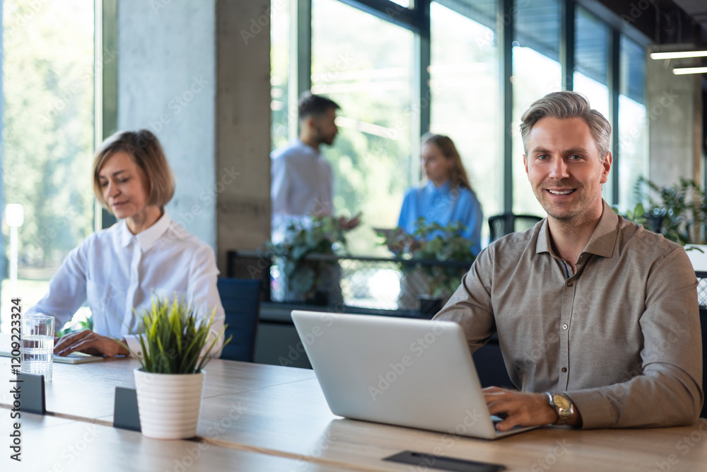 Businesspeople in formalwear working on laptop and PC in the modern office with colleagues on the background. Businesspeople in formalwear working on laptop and PC in the modern office with colleagues on the background.