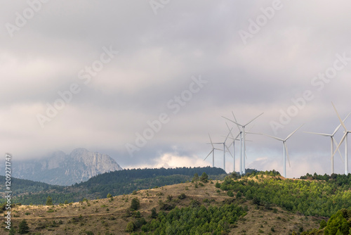 A series of wind turbines seamlessly integrated into the lush green hills illustrates the harmony between nature and renewable energy technologies in Navarra Spain photo