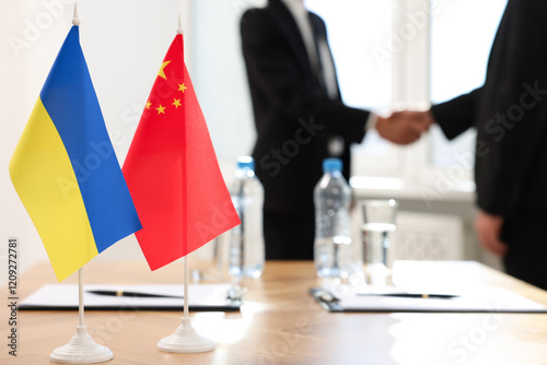 Diplomats shaking hands during meeting indoors, focus on flags of Ukraine and China photo