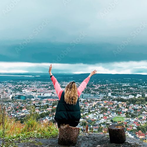Girl on top of rock overlooking city 