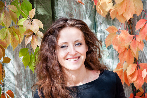Fall portrait. Girl smiling in autumn style has curly hair. Fall girl style fashion. Woman hair care. Woman portrait outdoor. Autumn leaves and young girl. Millennial woman in autumn park