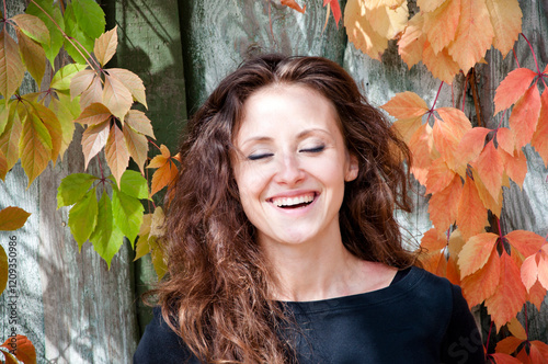 Millennial woman happy in autumn park. Fall portrait. Girl in autumn style has curly hair. Fall girl style fashion. Woman hair care. Woman portrait outdoor. Autumn leaves and young girl