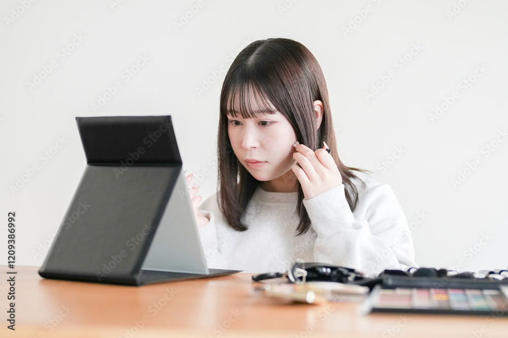 A young Japanese woman in her 20s is sitting in a tatami room and applying makeup using professional makeup tools.