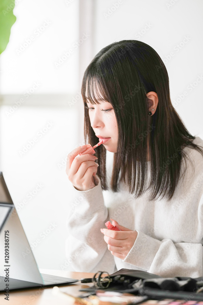 A young Japanese woman in her 20s is sitting on a chair and applying makeup using professional makeup tools. A young Japanese woman in her 20s is sitting on a chair and applying makeup using professional makeup tools.