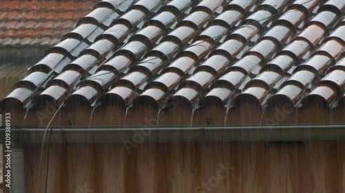 Torrential rain on the roof of a house. 4K resolution.
View of the wet tiles, shiny from the water reflection, creating a visual pattern with contrast. photo