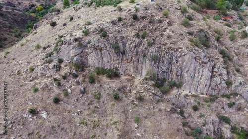 Imagen aérea con movimiento hacia atrás de una pared de roca con escaladores photo