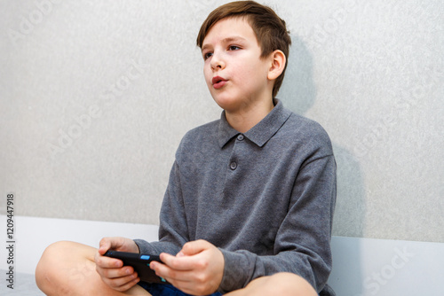 A ten-year-old boy breathes a sigh of relief after playing a challenging game on his smartphone.