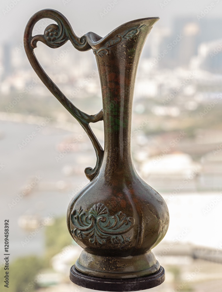 View of Antique carved iron jar or jug with riverview city and sky background. use it as your Wallpaper, Poster and Copy space, Selective focus.