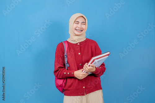 A young woman wearing a red sweater and a white skirt is holding a red book and a red backpack. She is smiling and giving a thumbs down gesture. Concept of casualness and nonchalance