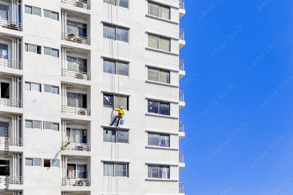 Workers are rappelling outside the building to paint it Workers are rappelling outside the building to paint it