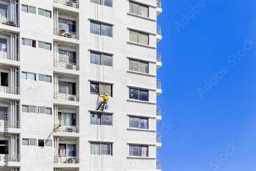 Fototapeta Naklejka Na Ścianę i Meble -  Workers are rappelling outside the building to paint it