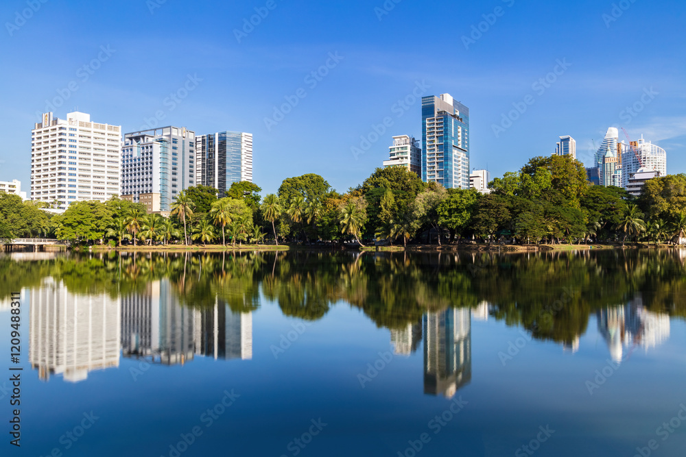 Fototapeta premium Skyline of Bangkok, Thailand, viewed from Lumphini park across the lake. Reflection of skyline in the water.
