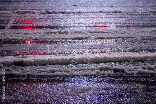 A dirty street road covered in snow and ice with a car tire track in the middle. Concept of danger and caution, as the wet and slippery surface can cause accidents. Cold season concept. photo