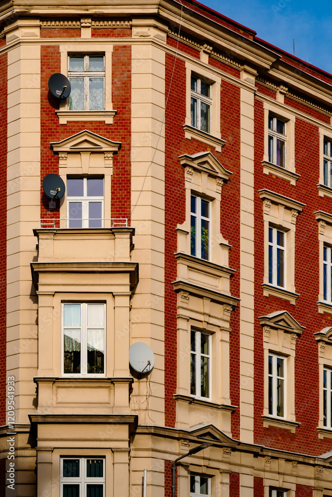 Naklejka premium Brick apartment building with satellite dishes in urban setting under clear blue sky