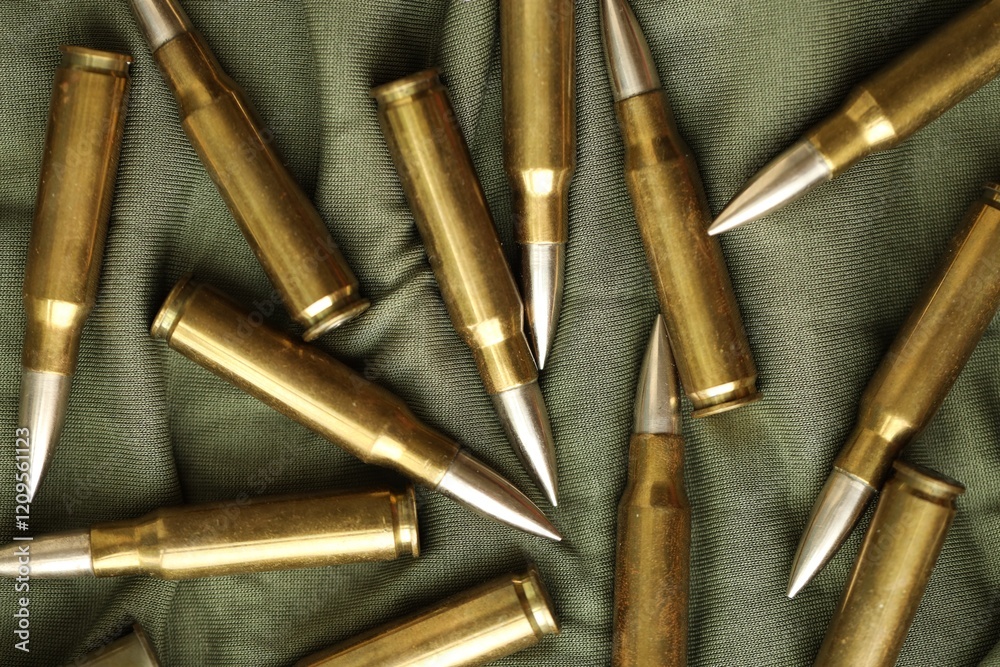 Many rifle bullets on military camo green fabric background Many rifle bullets on military camo green fabric background