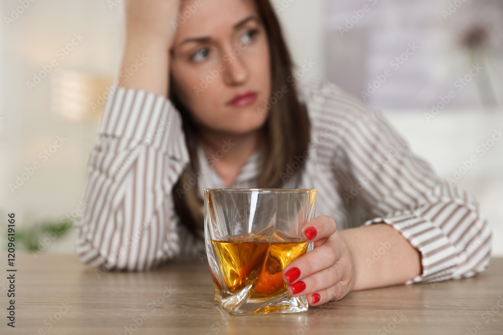 Alcohol addiction. Woman with glass of whiskey at wooden table indoors, selective focus Alcohol addiction. Woman with glass of whiskey at wooden table indoors, selective focus