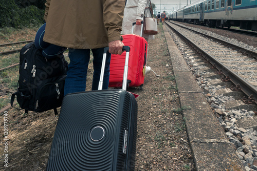 People with suitcases walking along the side of the railway