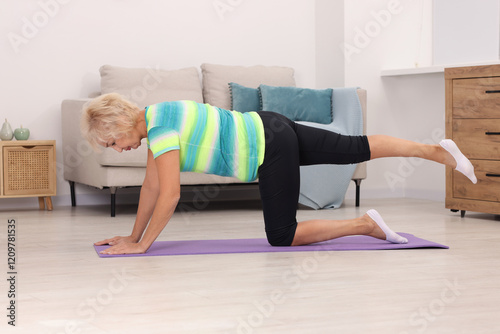 Senior woman exercising with fitness mat at home