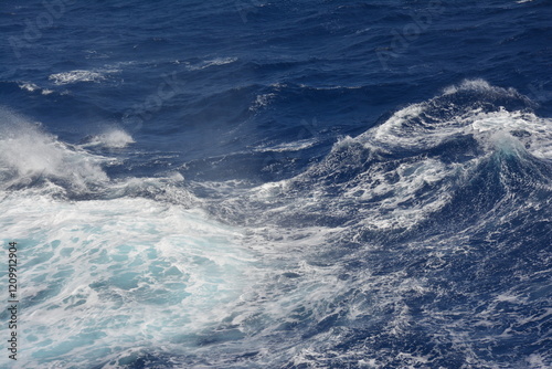 Fototapeta Naklejka Na Ścianę i Meble -  Choppy ocean waves with shades of deep blue and white foam. The dynamic movement of the water captures the power and turbulence of the sea
