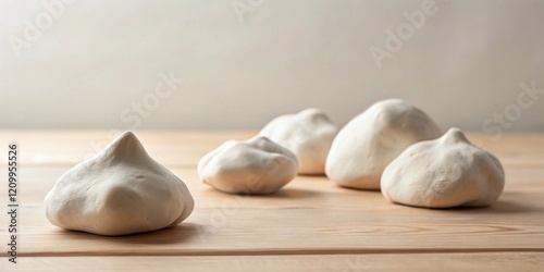 Close-up of five off-white, irregular shaped mounds on a light wood surface