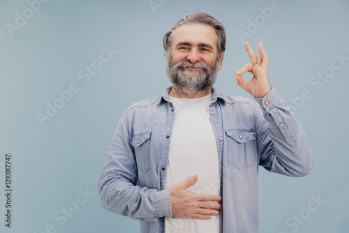 Fotografie Smiling senior man touching belly showing ok sign feeling good after taking medi