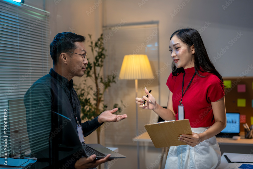 Asian business people having conversation about work in office at night