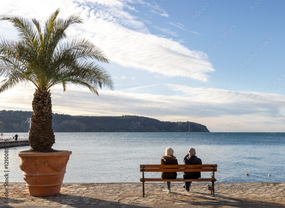 Older couple sitting by the sea and looking at the horizon