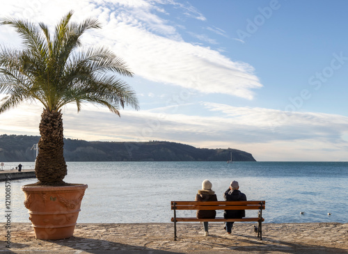 Obraz na płótnie Older couple sitting by the sea and looking at the horizon w salonie