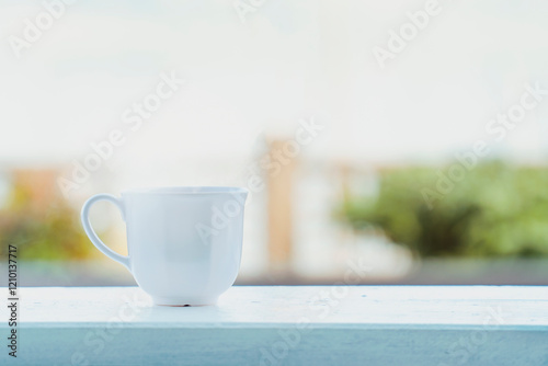 Cozy white coffee cup with steam on a wooden railing, bright morning scene with natural blurred background
