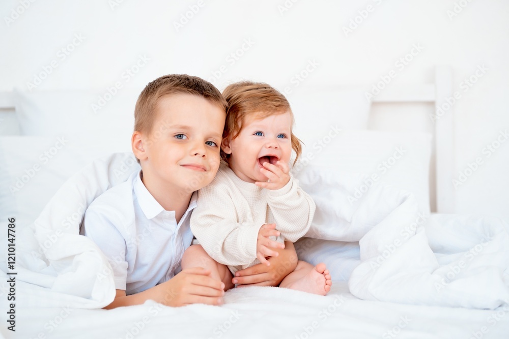 Brother hugs smiling younger brother, brotherly love and care, two children on the bed close-up Brother hugs smiling younger brother, brotherly love and care, two children on the bed close-up