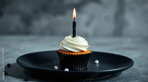 A single monochrome cupcake with pure white frosting and a sleek black candle, placed to the side of a matte black ceramic plate