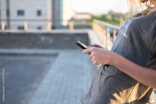 Close-up side view of a Woman  in a t-shirt standing in the street using her mobile phone photo