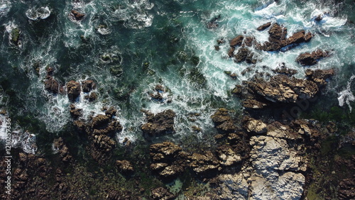 A breathtaking aerial drone view of the rugged rocks and tranquil sea off Asilomar Beach, nestled in the picturesque Del Monte Forest, California, capturing the beauty of the Pacific coastline at its 