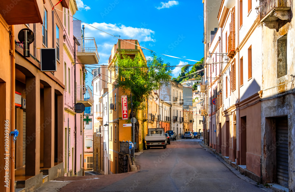 Obraz premium Idyllic, deserted street scene in the picturesque mountain village of Baunei on the Italian Mediterranean island of Sardinia. Main street lined with colorfully painted old houses on a hot summer day.