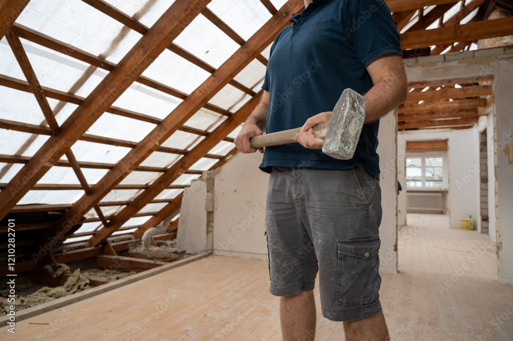 Fototapeta premium A handyman with a hammer during the renovation of the attic in a private house.