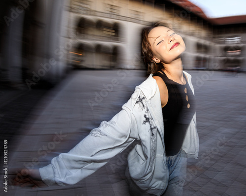 Obraz na płótnie Portrait of beautiful teen girl standing against ancient building, motion blur on the background is intentional w salonie