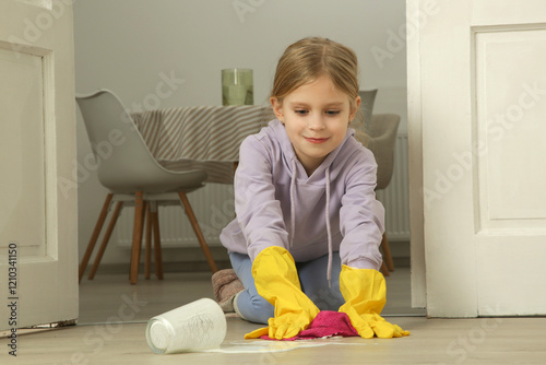 Little girl cleaning spilled milk on the floor photo