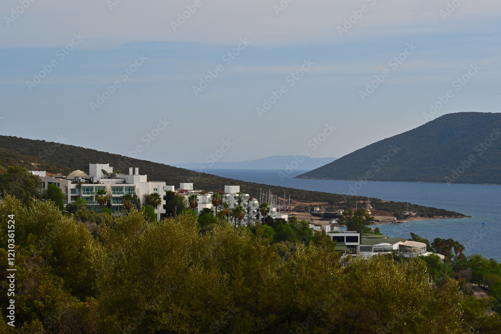 Obraz premium View from Turkish mainland near town of Bodrum, Mugla region, on the sea with boats and island Kara Ada. There are also some white buildings of hotels and tourist resorts.