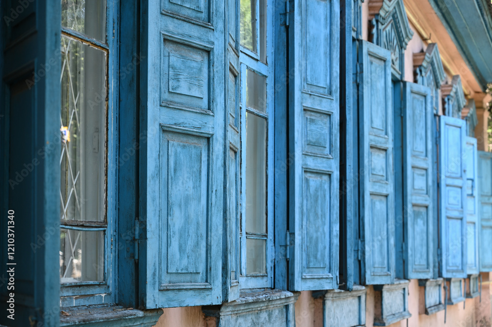 Wooden shutters of an old single-story traditional house. The wood is painted blue. City of Almaty, streets.