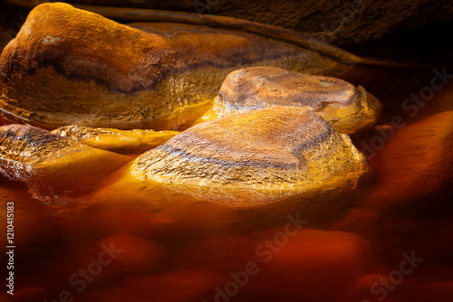 rocas en las aguas rojas ácidas, con alto contenido en metales pesados: hierro (el más abundante), cobre, cadmio, manguito de hierro en las aguas rojas de Río Tinto en Huelva, España que se asemeja a  photo