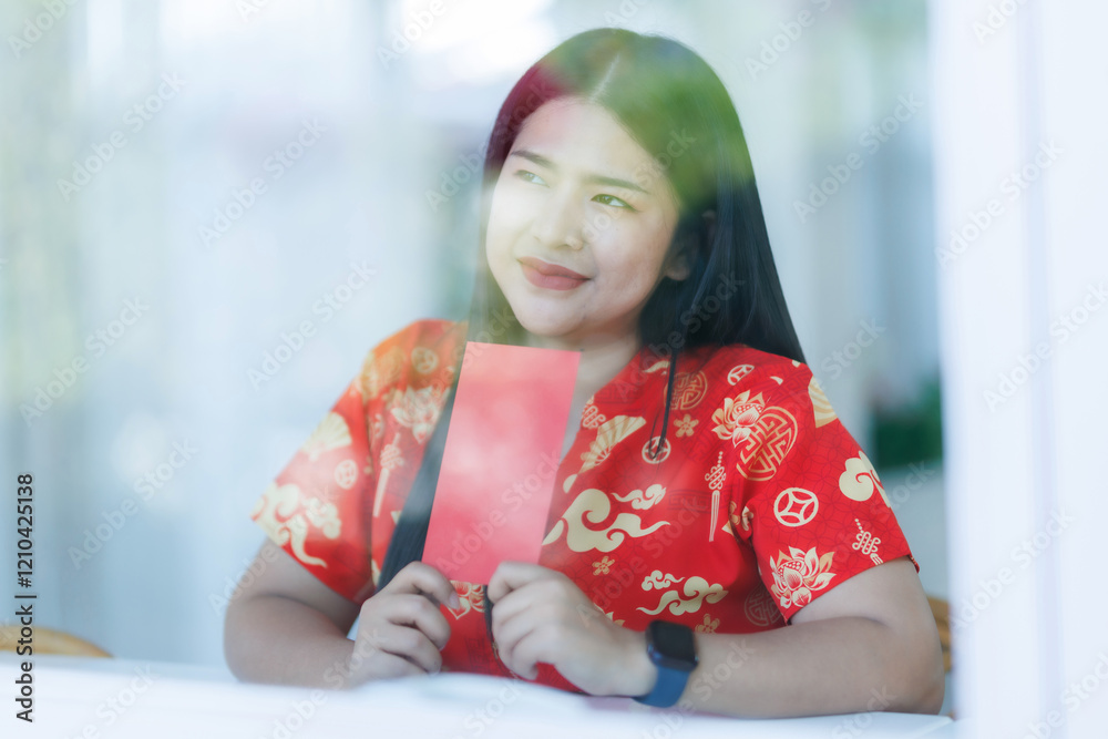 Portrait of happy asian woman relaxing wearing red cheongsam dress holding red envelopes at home in the living room indoor decoration for Chinese new year festival celebrate culture of china holiday