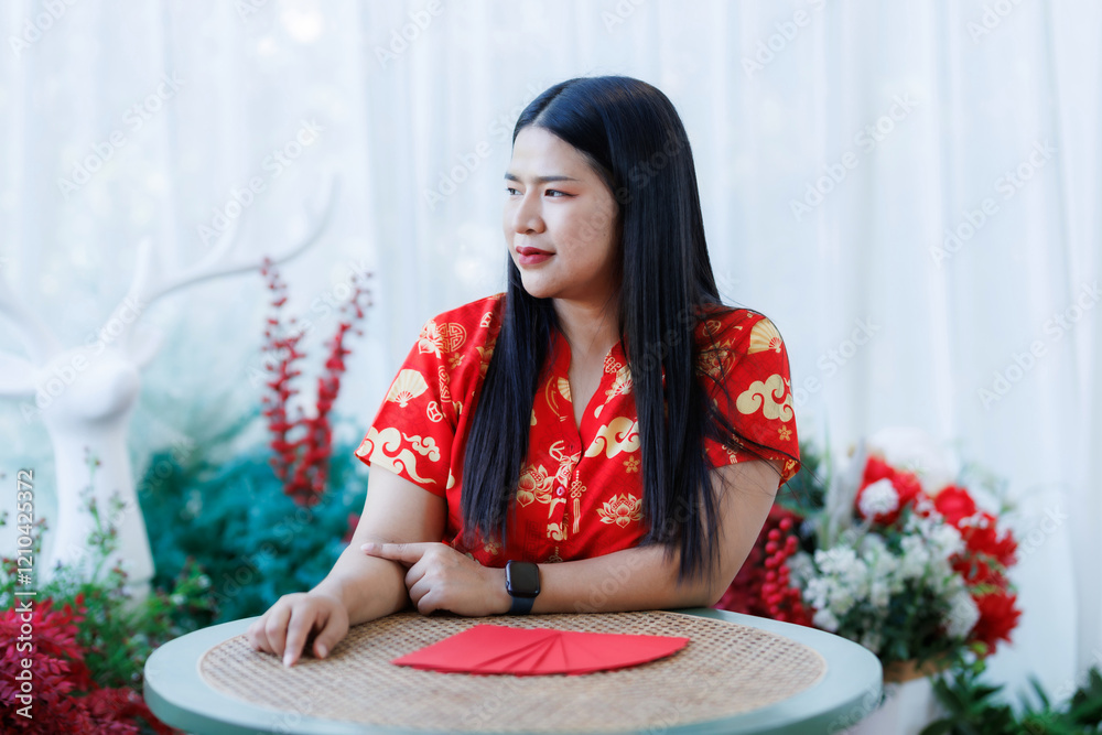 Portrait of happy asian woman relaxing wearing red cheongsam dress holding red envelopes at home in the living room indoor decoration for Chinese new year festival celebrate culture of china holiday