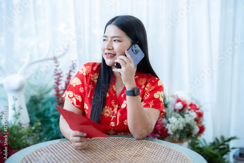 Obraz na płótnie Portrait of asian woman wearing red cheongsam dress holding red envelopes and smartphone at home in the living room indoor decoration for Chinese new year festival celebrate culture of china holiday w salonie