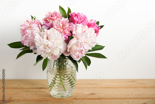 Wallpaper Mural Beautiful bouquet of fresh pink and white peonies in a glass vase sitting on a wooden table against a white wall Torontodigital.ca