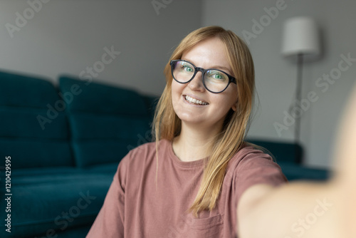 Obraz na płótnie Petty blond woman 30s wearing pink t-shirt smiling while looking at camera and taking selfie photo in living room. Online communication concept. High quality photo w salonie