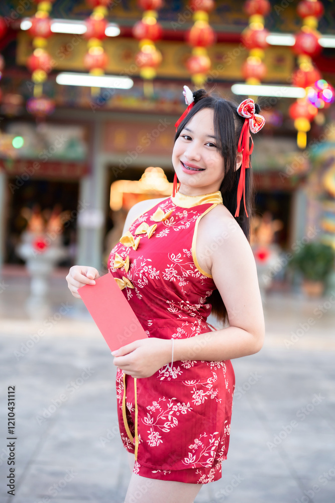 Portrait smiles Asian young woman wearing red cheongsam dress holding red envelopes decoration for Chinese new year festival celebrate culture of china at Chinese shrine Public places in Thailand