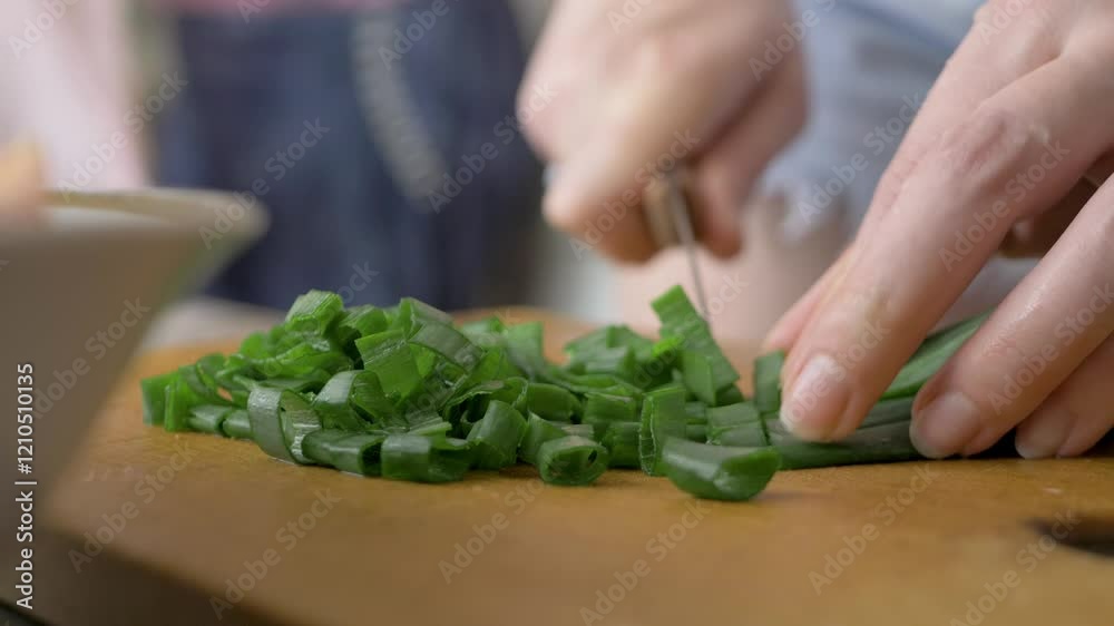 Green onion sprouts are sliced by hostess, prepares food in home kitchen for family. Incorporate fresh and flavor vegetables, making meal nutritious. Brown wooden background. Cook salad Green onion sprouts are sliced by hostess, prepares food in home kitchen for family. Incorporate fresh and flavor vegetables, making meal nutritious. Brown wooden background. Cook salad