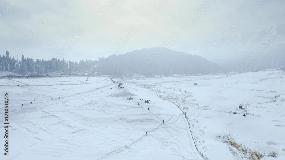 Aerial drone slow pan shot showing golf course strawberry garden in gulmarg kashmir covered in snow and people walking on it with the himalaya mountains in the distance Aerial drone slow pan shot showing golf course strawberry garden in gulmarg kashmir covered in snow and people walking on it with the himalaya mountains in the distance